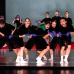 Danzatori in costumi neri e guanti di lattice viola in una coreografia di Marlene Monteiro Freitas